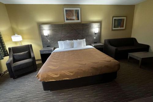 a hotel room with a bed and a chair at Quality Inn near I-72 and Hwy 51 in Forsyth