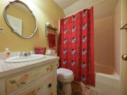 a bathroom with a sink and a red shower curtain at The Glory Glory Doghouse Main House Huge Yard in Athens