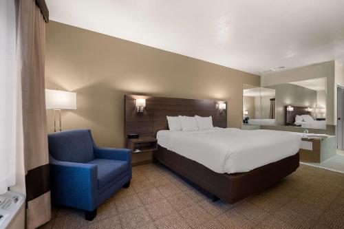 a bedroom with a large bed and a blue chair at Comfort Inn & Suites in Fenton