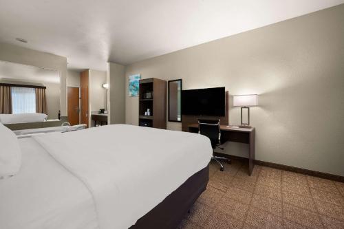 a hotel room with a bed and a desk with a television at Comfort Inn & Suites in Fenton