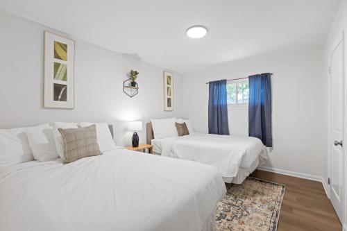 ein weißes Schlafzimmer mit 2 Betten und einem Fenster in der Unterkunft Elegant in Noir- Midcentury Modern Vibes in Chattanooga