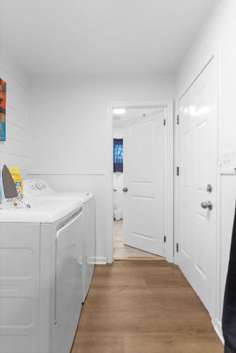 a white kitchen with white appliances and a hallway at Elegant in Noir- Midcentury Modern Vibes in Chattanooga