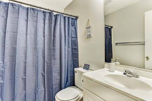 a bathroom with a blue shower curtain and a sink at The Groovy Getaway on Garfield in Savannah