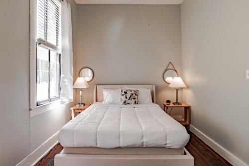 a white bedroom with a large bed with two lamps at Mins from Downtown & Dining, Dauphin Darling 2 in Mobile