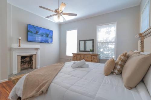 a white bedroom with a large bed and a fireplace at Mighty Mildred- Historic-Walkable-Mins to Riverwalk in Columbus