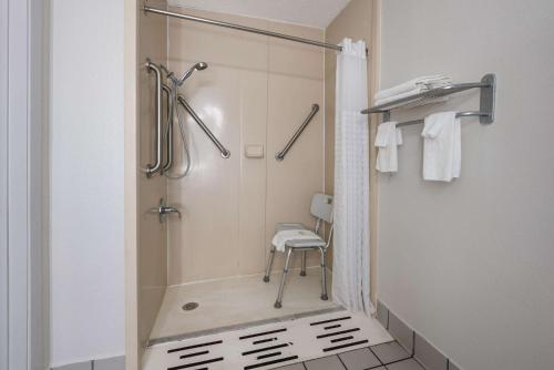 La salle de bains est pourvue d'une douche et d'une chaise. dans l'établissement Quality Inn University Area, à Farmville