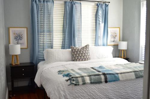 a bedroom with a bed and two windows with blue curtains at Perfectly Modern Craftsman- close to everything! in Mobile