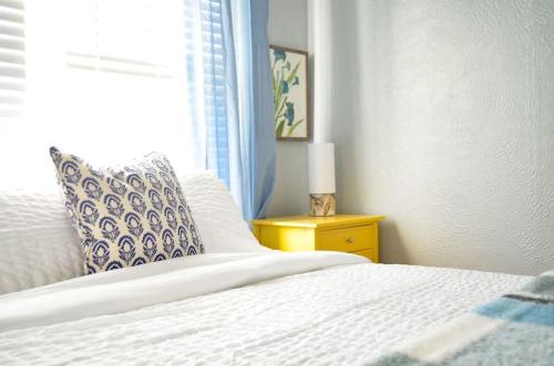 a bedroom with a white bed and a yellow night stand at Perfectly Modern Craftsman- close to everything! in Mobile