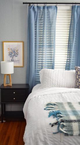 a bedroom with a bed and a window with blue curtains at Perfectly Modern Craftsman- close to everything! in Mobile