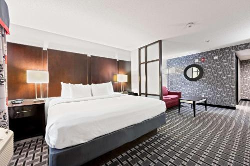 um quarto de hotel com uma cama grande e uma cadeira vermelha em Comfort Suites Williamsburg Historic Area em Williamsburg