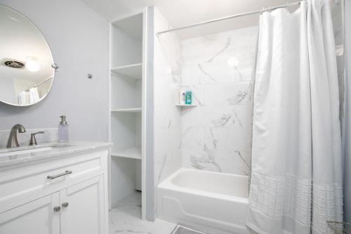 La salle de bains blanche est pourvue d'un rideau de douche et d'un lavabo. dans l'établissement Walking distance to Legion Field - Little Blue in Birmingham, à Birmingham