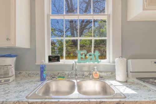 a kitchen sink in front of a kitchen window at The Sunny Southern Manse Back Walk Downtown in Columbus
