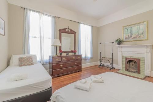 a bedroom with two beds and a dresser and a fireplace at The Sunny Southern Manse Back Walk Downtown in Columbus