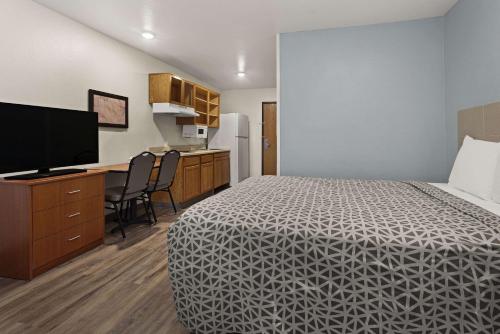 a room with a bed and a desk and a kitchen at WoodSpring Suites Augusta Fort Eisenhower in Augusta