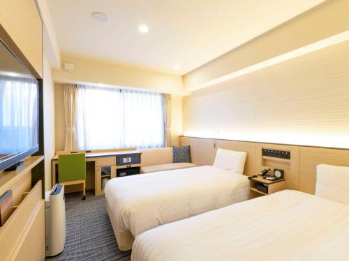 Comfort Inn Kyoto Shijokarasuma في كيوتو: غرفة فندقية بسريرين وتلفزيون بشاشة مسطحة