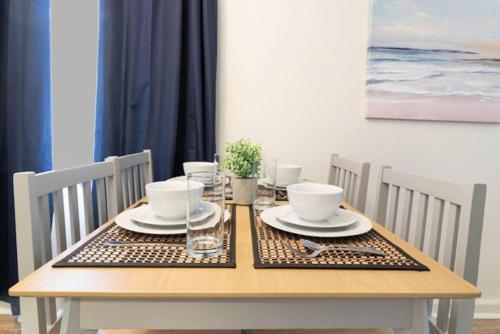 a wooden table with plates and bowls on it at The Delightful Doubles- Unit E- Centrally Located in Columbus