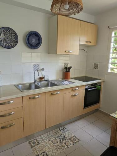 a kitchen with wooden cabinets and a sink and a stove at L'orchidée de Montebello in Petit-Bourg