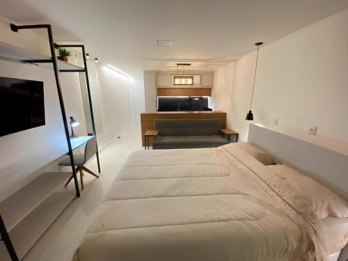 a white bedroom with a bed and a kitchen at Flat Home Business 202 Centro Pomerode in Pomerode