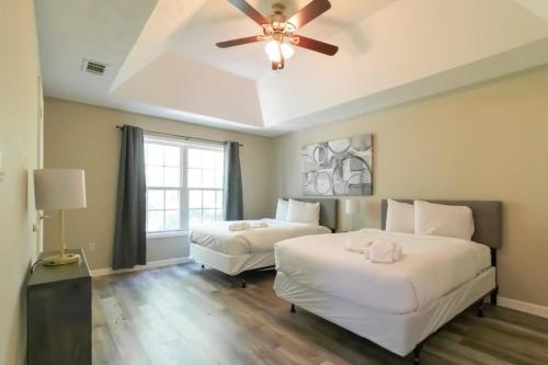 two beds in a room with a ceiling fan at Minutes to Benning Two-Story Oasis Benning Bliss in Columbus