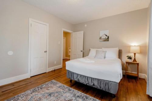 a bedroom with a large white bed and wooden floors at Mins to USC, Hospital, Zoo! Columbia Duet- 2 Units in West Columbia
