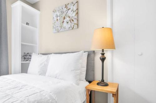 a bed with white sheets and a lamp on a table at Two Kitchens Family Friendly in Forestdale in Birmingham
