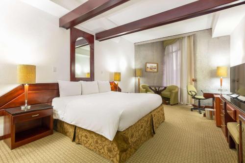 サンホセにあるラディソン ホテル サンノゼ コスタリカの大きなベッドとデスクが備わるホテルルームです。