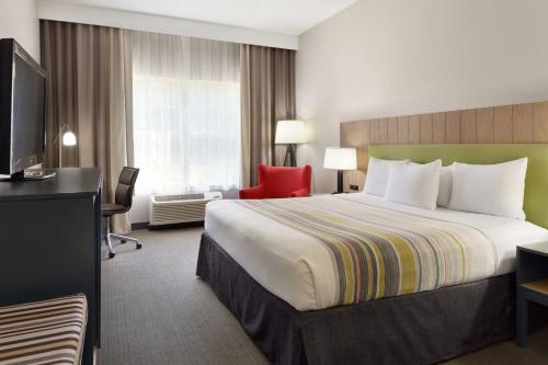 ein Hotelzimmer mit einem großen Bett und einem roten Stuhl in der Unterkunft Country Inn & Suites by Radisson, Brunswick I-95, GA in Brunswick