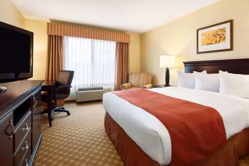 a hotel room with a large bed and a flat screen tv at Country Inn & Suites by Radisson, Clinton, IA in Clinton