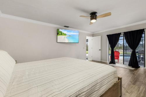 ein weißes Schlafzimmer mit einem Bett und einem Deckenventilator in der Unterkunft Palmetto Pines Paradise in Cape Coral