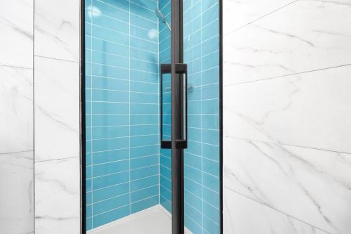 a glass shower in a bathroom with blue tiles at Waterside 4 Bed Apartment in London