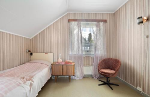 Casita Aurora Residence في ترومسو: غرفة نوم بسرير وكرسي ونافذة