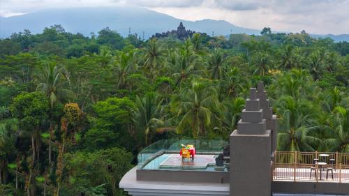 a building with a view of a forest of palm trees at Hotel Le Temple Borobudur in Borobudur