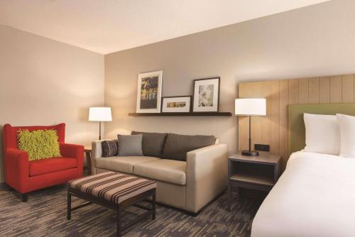 a hotel room with a bed and a couch and a chair at Country Inn & Suites by Radisson, Green Bay North, WI in Green Bay
