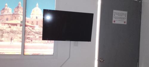 TV de pantalla plana colgada en una pared junto a una ventana en Hotel Río Mar, en Cartagena de Indias