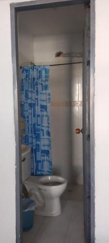 a bathroom with a toilet and a blue shower curtain at Hotel Río Mar in Cartagena de Indias