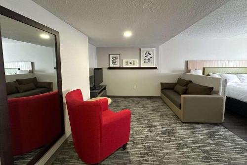 una camera d'albergo con una sedia rossa e un letto di Country Inn & Suites by Radisson, Dunbar, WV a Dunbar