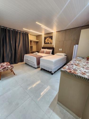 a hotel room with two beds and a table at Flats Bahia in Coruripe