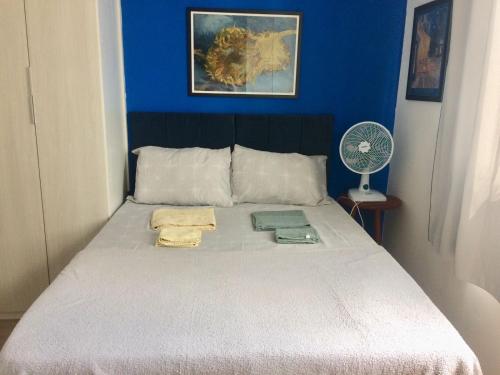 1 dormitorio con 1 cama con pared azul y ventilador en Aconchegante estúdio para sua estadia!, en São Paulo