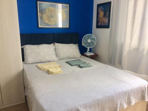 a bedroom with a white bed with a blue wall at Metrô p Allianz Park e Espaço Unimed, Compras no Brás - Excelente! in Sao Paulo