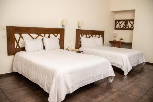 two beds in a room with white sheets at Hotel Tres Soles in Ciudad Madero