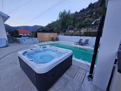 a hot tub sitting on a patio next to a pool at Alfatima in Manteigas