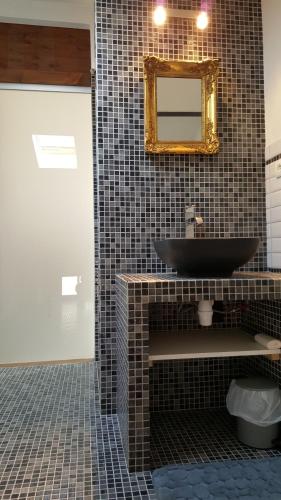 une salle de bain avec un lavabo noir et un miroir dans l'établissement Appartement Corse Extrême-Sud, à Monacia-dʼAullène