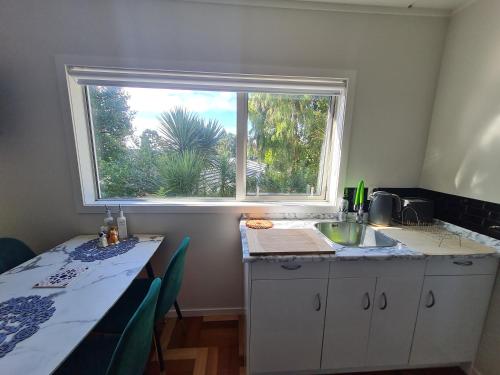 eine Küche mit einem Fenster und einer Theke mit einem Tisch in der Unterkunft Paris studio in Auckland
