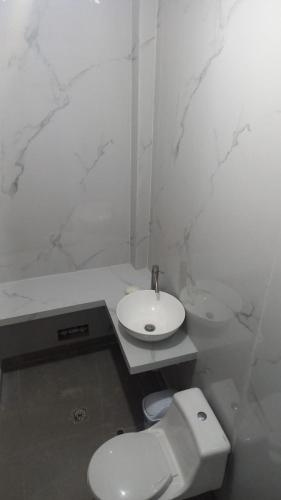 a white bathroom with a toilet and a sink at Hospedaje Mi Casita - Pucallpa -Selva in Puerto Callao