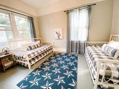 a living room with two beds and a blue rug at Modern & Centrally Located Stay at Calypso Dreams in Mobile
