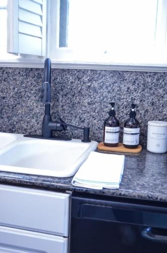 a kitchen counter with a sink and two bottles of soap at Modern & Centrally Located Stay at Calypso Dreams in Mobile