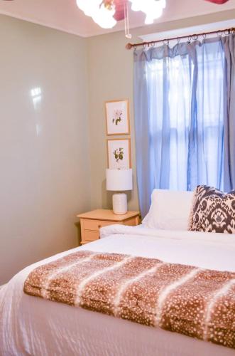 a bedroom with a bed and a window with blue curtains at Modern & Centrally Located Stay at Calypso Dreams in Mobile
