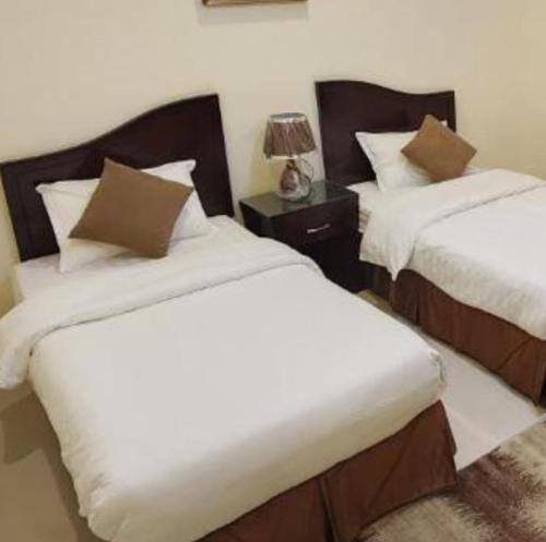 a bedroom with two beds with white sheets and a lamp at جراند روزالينا جازان in Bakhshat Yamanī