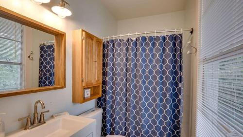 a bathroom with a blue shower curtain and a sink at Flamingle in Fushia- Unit A- Steps to the Beach! in Tybee Island
