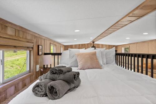 1 dormitorio con 1 cama blanca grande y toallas. en Big-Tiny Home Farm Stay-15Min to Chattanooga en Wildwood